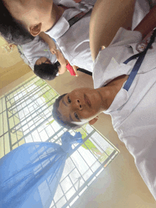 a man in a white shirt with a blue ribbon around his neck has a watch on his left wrist