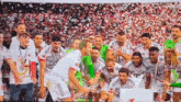 a group of soccer players are posing for a picture with a trophy