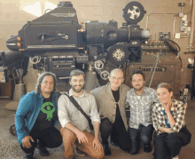 a group of people posing for a picture in front of a machine that says ' ford ' on the front