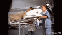 a nurse pushes a patient on a stretcher with a gifrun.com watermark