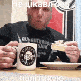 a man in a misanthropist shirt is eating a sandwich