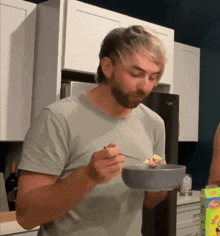 a man is eating cereal from a bowl with a spoon in his hand