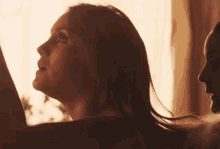 a woman with long hair looks up at the sun