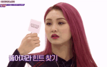 a woman with pink hair is holding a card with the word secret number on it