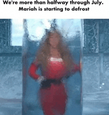 a woman in a red dress is standing in a glass container .