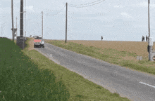 a car is driving down a road that is surrounded by grass