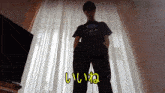 a man standing in front of a window with chinese writing on the bottom of his pants