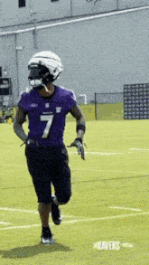 a football player is running on a field wearing a purple jersey and a helmet .