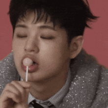 a close up of a person eating a lollipop with their eyes closed