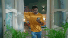 a man in a yellow sweater looks at his phone