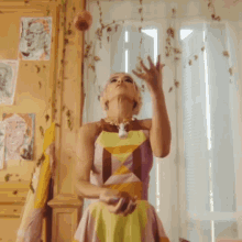 a woman in a colorful dress is juggling an apple in her hand