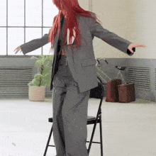 a woman in a suit is standing on a chair