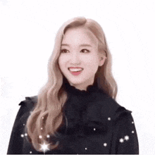 a woman with long blonde hair is smiling and wearing a black dress with stars on it .