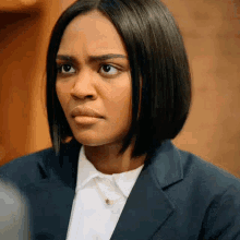 a woman in a suit and white shirt is looking at the camera