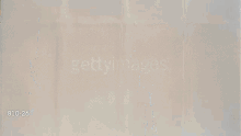 a man in a white suit is standing in front of a wall that says " gettyimages "