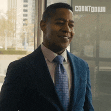 a man in a suit and tie is smiling in front of a sign that says " countdown "
