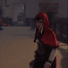 a woman in a red hooded cape points to something