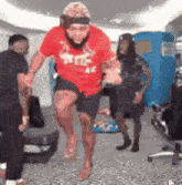 a man in a red shirt is jumping in the air while a group of people watch .
