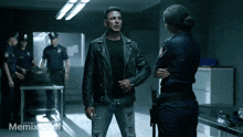 a man in a leather jacket is standing next to a police officer and the website memix.com is visible in the corner