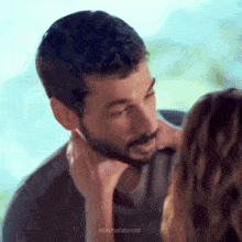 a man with a beard is kissing a woman 's neck .