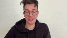a young man wearing glasses and a hoodie is making a funny face .