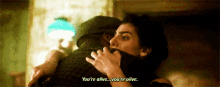 a woman is hugging a man in a room and saying `` you 're alive ... you 're alive '' .