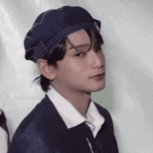 a young man wearing a blue hat and a white shirt is making a funny face .