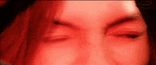 a close up of a woman 's face with a red light behind her .