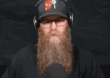 a man with a beard and glasses is wearing a hat and headphones .