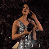 a woman in a sequined dress holds a camera in her hand