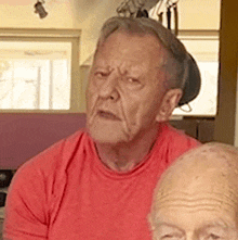 a man wearing a red shirt looks at the camera