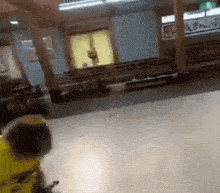 a person in a yellow jacket is standing in a room with a lot of empty seats .