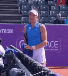 a woman in a blue shirt is standing in front of a purple wall that says ace