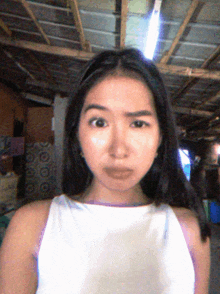 a woman in a white tank top has a serious look on her face