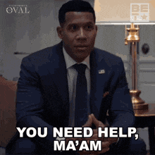 a man in a suit and tie is sitting on a couch and says you need help ma 'am
