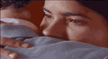 a woman is covering her face with a blanket while a man holds her head .