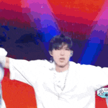 a man in a white shirt is standing on a stage with his arms outstretched in front of a colorful background ..