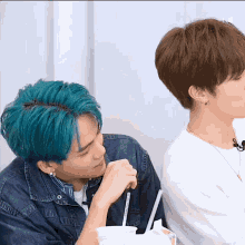 a man with blue hair sitting next to another man