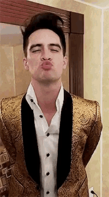 a man in a tuxedo is blowing a kiss .