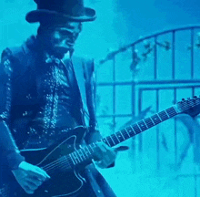a man in a top hat is playing a guitar in a dark room