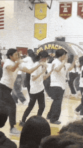 a group of people are dancing in front of a banner that says apacs