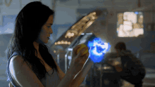 a woman is holding a yellow object with a blue light coming from it