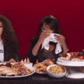 a woman covering her mouth with a napkin while eating food