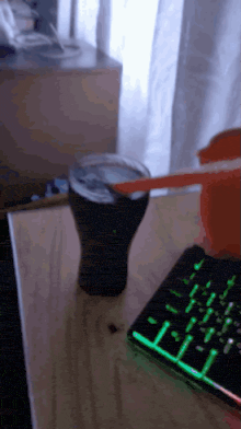 a cup of coke sits on a table next to a keyboard