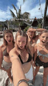 a group of women taking a selfie on a beach with koh rong cambodia in the corner
