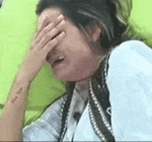a woman is crying while covering her face with her hand .
