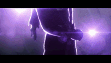 a person is standing in a dark room with a purple light shining on them