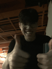 a man wearing glasses is giving a thumbs up sign