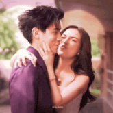 a man in a purple suit kisses a woman in a white dress who is making a funny face