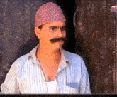 a man with a mustache wearing a striped shirt and a hat is standing in front of a door